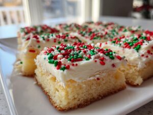 Close-up of soft, thick christmas sugar cookie bars topped with white frosting and festive red, green, and white sprinkles.
