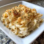 A close-up of a serving of creamy chicken noodle casserole topped with golden breadcrumbs and parsley.