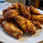 A close-up pile of golden brown, crispy air fryer chicken wings seasoned and ready to eat.