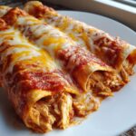 Close-up of three easy chicken enchiladas covered in red sauce and melted cheddar and Monterey Jack cheese.