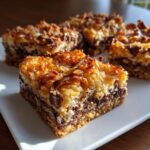 Close-up of a square portion of magic cookie bars showing the crust, chocolate chips, and toasted coconut topping.