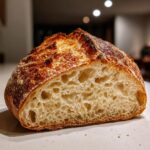 Close-up of a freshly baked Italian bread loaf cut in half, showing an open, airy crumb structure.
