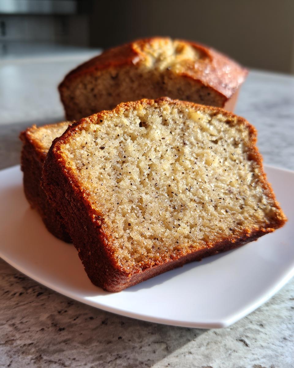 Close-up of two moist slices of greek yogurt banana bread on a white plate, with the loaf blurred in the background.