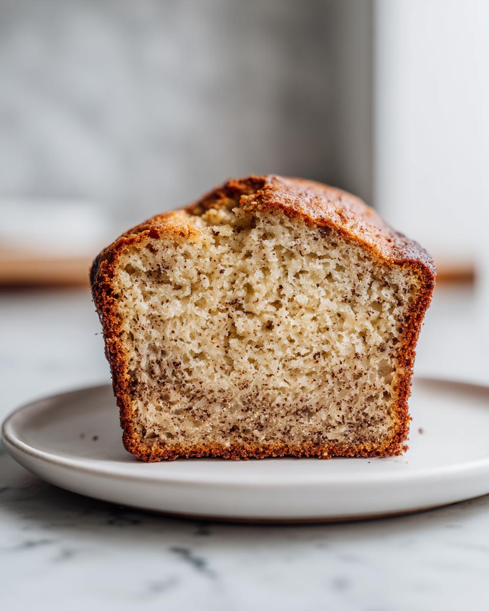 Close-up of a thick slice of moist greek yogurt banana bread showing the soft crumb texture and browned crust.