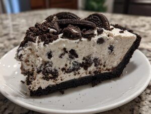 Close-up of a rich slice of no bake oreo pie showing the dark crust, creamy white filling with cookie chunks, and whole cookies on top.