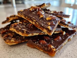 A stack of rich, homemade Pecan Pie Bark pieces topped with pecans and sea salt.
