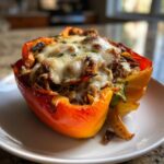 Close-up of a baked philly cheesesteak stuffed pepper, topped with melted white cheese and herbs.