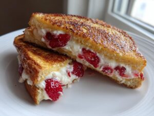 Close-up of golden brown stuffed french toast cut in half, revealing a creamy filling with fresh strawberry slices.