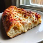 A thick slice of homemade cheese pizza showing extreme cheese pull and a fluffy crust.