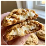 Close-up of caramel apple cookies cut in half showing a creamy white filling and caramel drizzle.