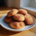 A stack of freshly baked churro cookies coated heavily in cinnamon sugar, resting on a light blue plate.