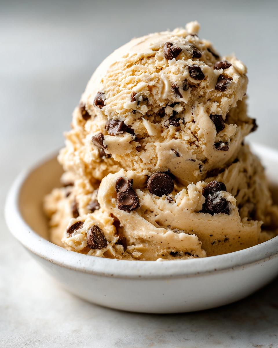 Two scoops of creamy, edible chocolate chip cookie dough recipe served in a small white bowl.