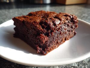 Close-up of a rich, fudgy square of date brownies sitting on a white plate.