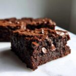 Close-up of a fudgy zucchini brownies square showing rich texture and melted chocolate chips.