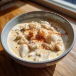 A close-up of a bowl of creamy, velvety crab soup generously topped with flaked crab meat and paprika.