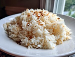 A mound of fluffy white butter rice topped with crispy, browned bits, served on a white plate.
