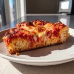 A thick, golden slice of pizza featuring a fluffy cottage cheese pizza crust topped with melted cheese and rich tomato sauce.